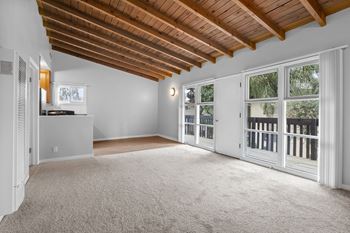 an empty living room with large windows and a balcony